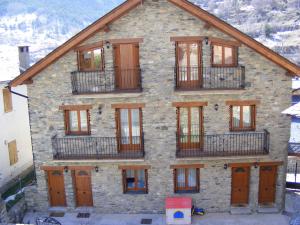 a stone house with wooden doors and balconies at Apartaments l'Arrel in Espot