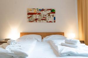 uma cama com lençóis brancos e toalhas em Central living - Stephansdom Apartments em Viena