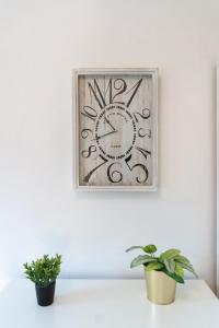 a clock on a white wall with two potted plants at Central living - Stephansdom Apartments in Vienna