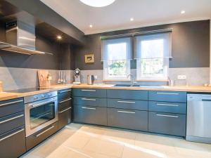 une grande cuisine avec des armoires bleues et des fenêtres dans l'établissement Countryside Holiday Home in Durbuy with Terrace, à Durbuy