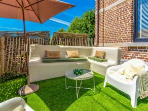 un patio con sofá, mesa y sombrilla en Luxurious holiday home in Heers with terrace en Mettekoven