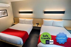 a hotel room with two beds and a sign that says safe travels at City Express Plus by Marriott Cali Colombia in Cali