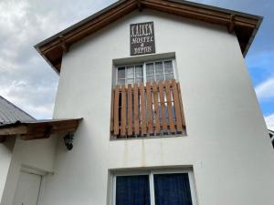 a white building with a window with a sign on it at Kaiken - Hostel & Departamentos in El Chalten