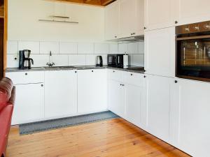 een witte keuken met witte kasten en een houten vloer bij Alluring Holiday Home in Fraiture with Infrared Sauna in Fraiture