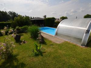 a swimming pool in a garden next to a metal building at Luxury Villa near Forest in Hlavice Czech Republic in Všelibice