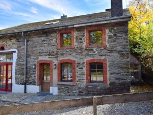 Petit-ThierにあるArdennic farmhouse for groupsの赤窓と赤い扉のある古い石造りの建物