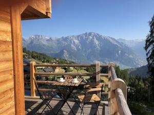 una mesa y sillas en un porche con vistas a las montañas en Top chalet with unobstructed view inthe ski resort en La Tzoumaz