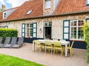 a patio with a table and chairs in front of a building at Historic Farmhouse in the middle of polder landscape Damme in Oedelem