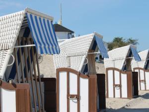 eine Reihe von Liegestühlen und Sonnenschirmen am Strand in der Unterkunft Bastorf Sea View Escape in Bastorf