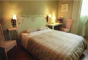 a bedroom with a large bed and two chairs at Hostal Fornos in Segovia