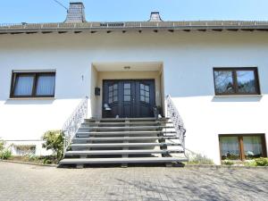a white house with stairs and a black door at Sun Kissed Apartment in Lirstal with Garden in Lirstal