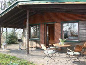 uma cabana com uma mesa e cadeiras e um cão em Dog friendly holiday home in the Kn ll em Neuenstein