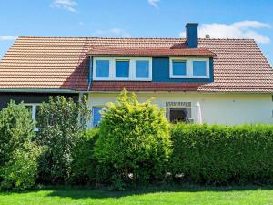 a house with a red roof and some bushes at Stylish apartment in Stormbruch with garden in Stormbruch