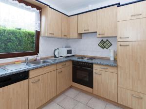 cocina con armarios de madera, fregadero y microondas en Holiday Home in Mielinghausen with Garden Terrace, en Reiste