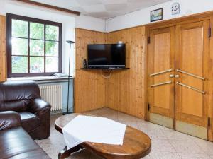 a living room with a couch and a table and a tv at Large group house beautifully located in Eifel in Ammeldingen