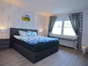 - une chambre avec un lit et une grande fenêtre dans l'établissement Modern holiday home idyllic setting with terrace, à Medebach