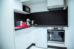 uma cozinha com armários brancos e um forno com placa de fogão em SECRET SUITE "Mr Grey" - Jacuzzi privatif - Gare RER C - Proche Paris em Brétigny-sur-Orge