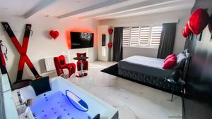 a bedroom with a bed and a table and red chairs at SECRET SUITE "Mr Grey" - Jacuzzi privatif - Gare RER C - Proche Paris in Brétigny-sur-Orge