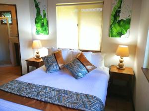 sypialnia z łóżkiem z poduszkami i 2 lampami w obiekcie Poppy's on the Lagoon w mieście Port Vila