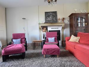 a living room with a red couch and two chairs at Holiday home with private heated pool in Villiers-les-Moines