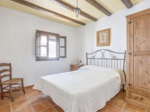sypialnia z białym łóżkiem i krzesłem w obiekcie Villa in Carcabuey near Sierras Subbeticas Park w mieście Carcabuey