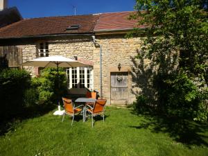 a table and chairs with an umbrella in front of a house at Holiday Home in Saizy with Patio in Vignol