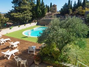 an outdoor deck with a pool and chairs and a yard at Stone cottage on an active wine growing estate with a swimming pool in Conilhac-Corbières