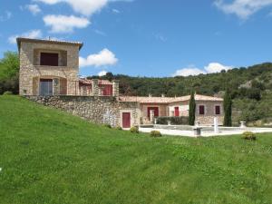 a stone house on a hill with a green field at Cosy holiday home with views and private pool in Saint-Ambroix