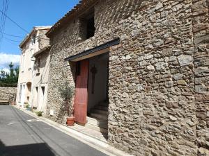 a brick building with a red door and a sidewalk at Holiday home near the Canal du Midi in Olonzac