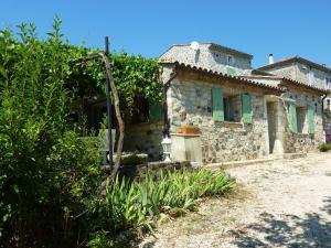 een oud stenen huis met groene luiken op een erf bij Peaceful holiday home with pool in Saint-Pons