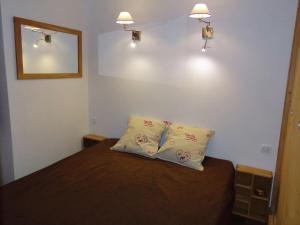 - une chambre avec un lit avec deux oreillers et un miroir dans l'établissement Simplistic Apartment in M ribel near Les 3 Vall es, à Méribel