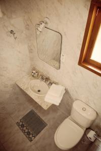 a bathroom with a toilet a sink and a mirror at Pousada Refugio do Serrano in São Bento do Sapucaí