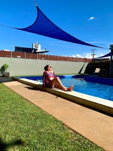 a woman sitting on a curb next to a swimming pool at Central Motel Mildura in Mildura