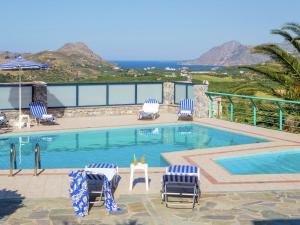 LefkogeiaにあるChic Villa in Lefkogia Crete with Swimming Poolの青と白の椅子と海を望むスイミングプール
