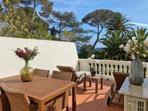 a patio with a wooden table and chairs and flowers at Apartment in villa with pool and beach access in Saint-Raphaël