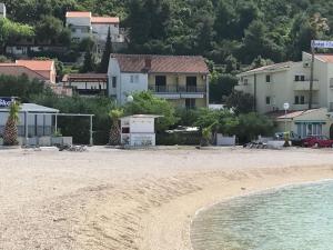 Spacious and modern apartment directly on the beach in Klek 70 km away from Dubrovnik في كليك: شاطئ رملي وبيوت في الخلف