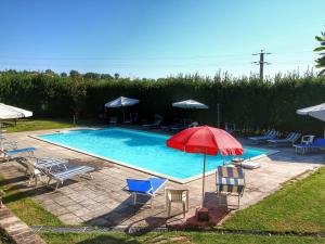 uma piscina com cadeiras e um guarda-sol vermelho em Belvilla by OYO Splendid Farmhouse with Jacuzzi em Gualdo Cattaneo
