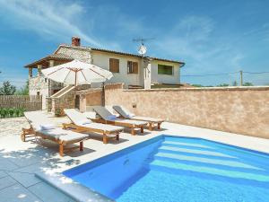 a pool with chairs and an umbrella next to a house at Modern Holiday Home in Porec with Swimming Pool in Nova Vas
