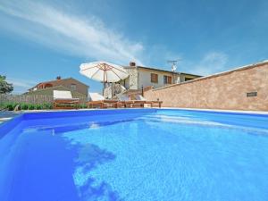 a large blue swimming pool with an umbrella at Modern Holiday Home in Porec with Swimming Pool in Nova Vas