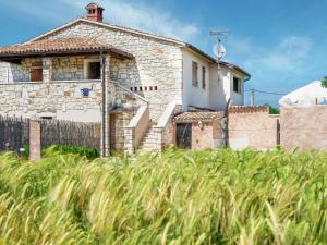 a stone house with a fence and tall grass at Modern Holiday Home in Porec with Swimming Pool in Nova Vas