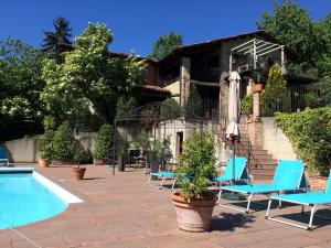 Bastia MondovìにあるBelvilla by OYO House with large terrace and poolのスイミングプール、青い椅子、パラソル付