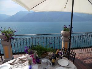 una mesa en un balcón con vistas al océano en Bright stylish facing the lake Large terrace with magnificent views en Marone