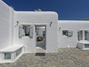 カラファティスにあるBeautiful large luxury villa in Mykonosの白い建物(パティオにベンチ2台付)