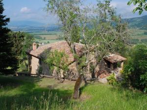 ein altes Steinhaus auf einem Hügel mit einem Baum in der Unterkunft Belvilla by OYO Nespolo Uno in Magione