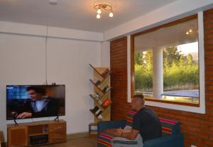 un hombre sentado en un sofá en una sala de estar viendo televisión en Runaway Eco Hotel, en Carhuaz