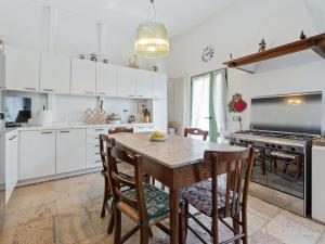Romano D'EzzelinoにあるBelvilla by OYO Villa Fiorita Dueの白いキャビネット、木製テーブルと椅子付きのキッチンが備わります。