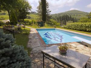 een zwembad in een tuin met een tafel ernaast bij Belvilla by OYO Uva in Radda in Chianti