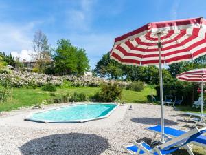 uma piscina com um guarda-sol e duas cadeiras e um guarda-sol em Belvilla by OYO La Cinciallegra em Acqualagna