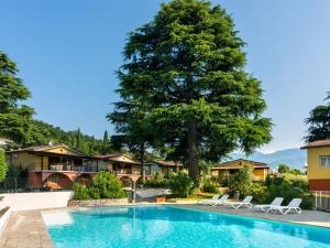 MontinelleにあるSerene Apartment in Manerba del Garda with Poolの木とラウンジチェア付きのスイミングプール