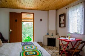 a bedroom with a bed and a table and a fireplace at Pousada Polessas in Visconde De Maua